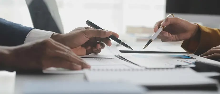 Two advisers reviewing printed financial charts at a table